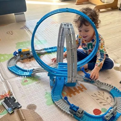 Enfant content assis au sol joue avec circuit voiture enfant