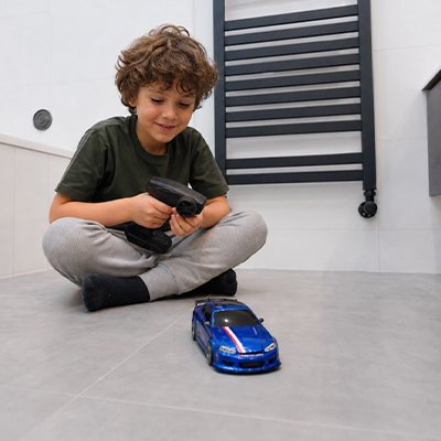 garçon assis au sol garage s'amuse avec voiture télécommandée enfant